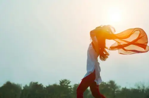 Femme dansant avec un foulard au levier du soleil, symbolisant la liberté et l'acceptation de soi